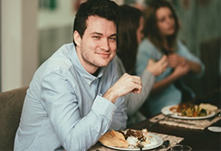Male resident enjoys meal with peers and faculty at Academic Dinner