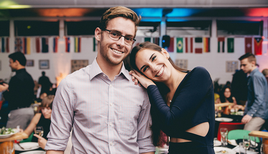 International night at UniHall with male resident smiling and female resident leaning on shoulder smiling