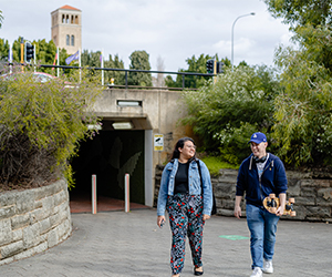 Image of two students walking back from campus with UWA's Winthrop Hall in the background