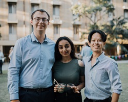 Image of three students standing together as friends at an event