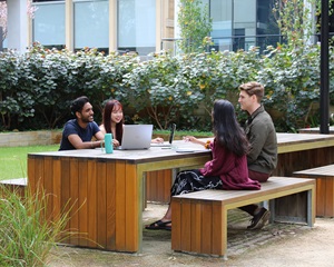 Image of four students studying together at an outdoor table at UniHall
