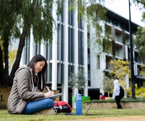 Image of student writing on notebook outside University Hall