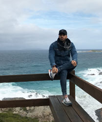 Image of Hamed sitting on a lookout on the seaside