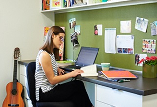 Female resident studying at desk in one bedroom apartment