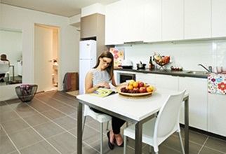 Female resident sitting at table in one bedroom apartment kitchen