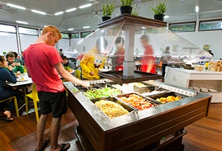 Male resident at salad bar serving caesar salad onto his plate