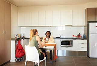 Two residents sitting in kitchen at dining table chatting over coffee