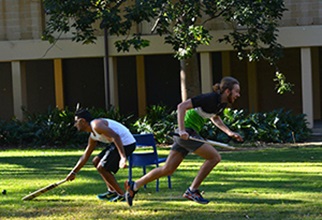 Two residents running in a cricket game at UniHall