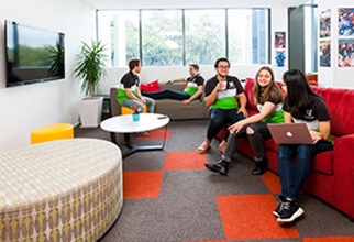 Group of residents watching tv, chatting, lying on the couch and studying on the laptop in the common room