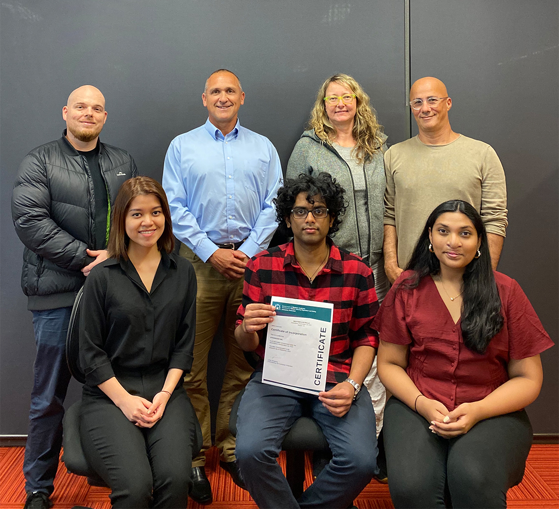 Image of student management team with University Hall staff and Unleash Design mentors with certificate of incorporation for Sites4Good