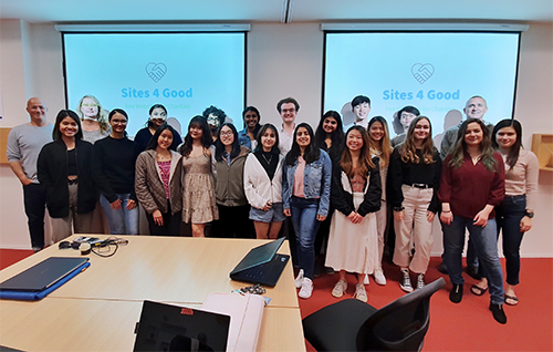 Image of students participating in the Semester 2 Sites4Good program with mentors, all standing in front of presentation screens that say Sites4Good